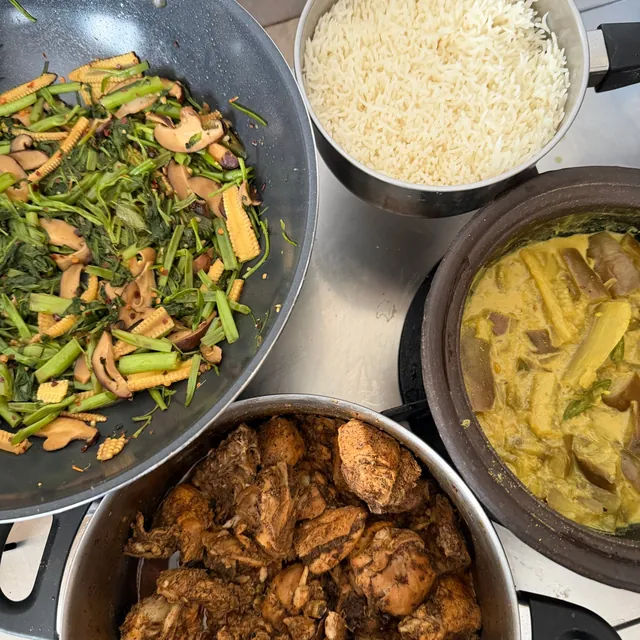 Pots of stir-fried greens, rice, a coconut curry and chicken curry