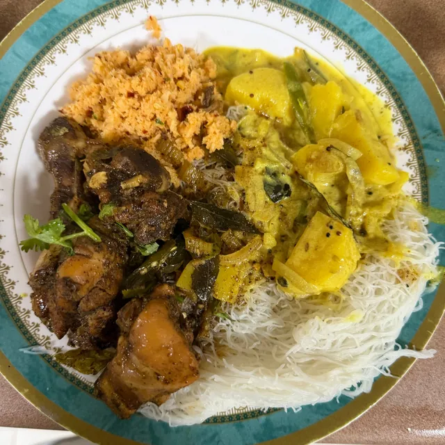 String hoppers with black chicken curry, potato curry and coconut sambol
